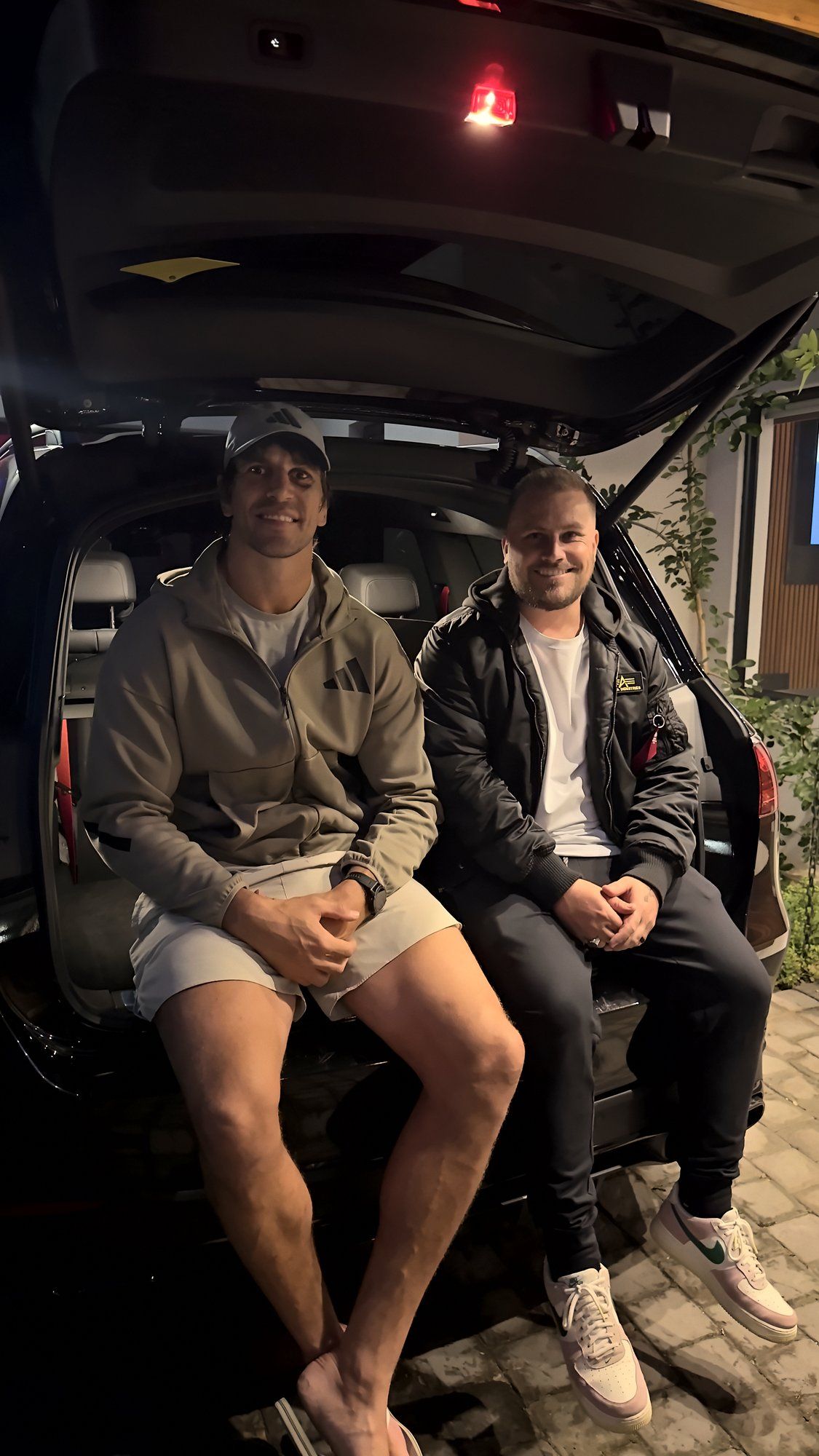 Eben Etzebeth × LivWell Studios campaign: two men sitting in the open boot of a car at night, lit by the boot light