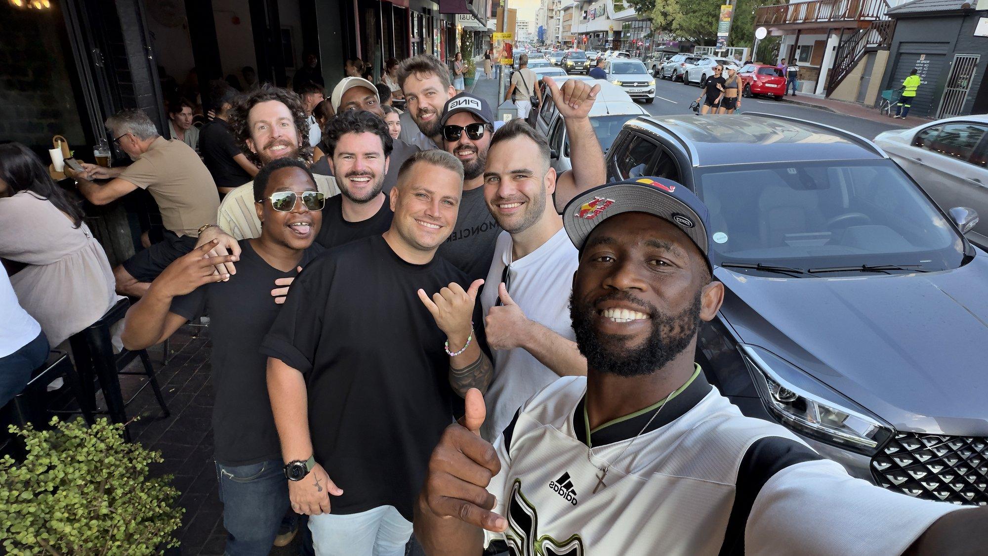 Siya Kolisi × Dunk ice baths campaign: a smiling group selfie with a crowd on a city street