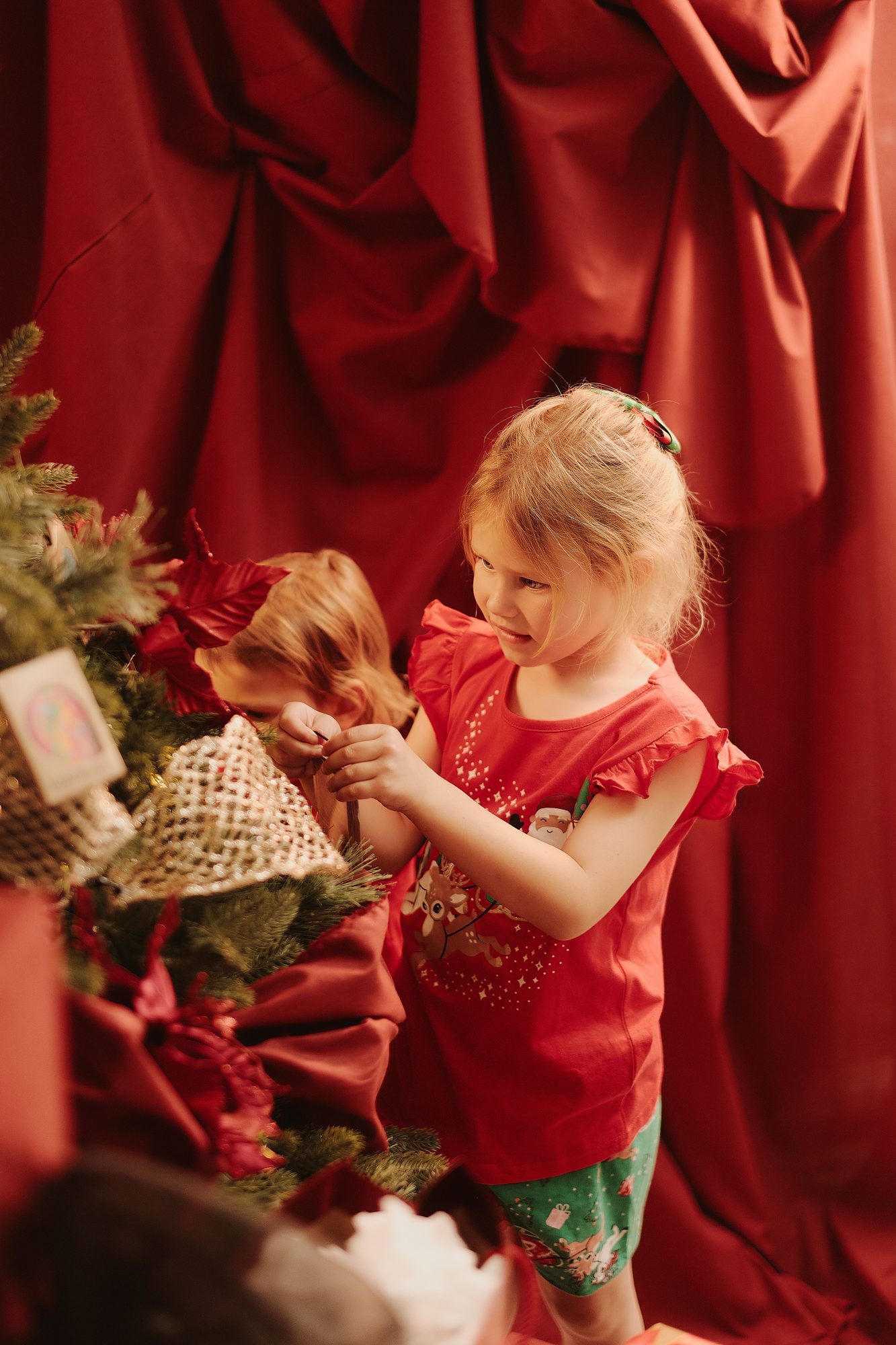 Boya: Child in red reaching for the Christmas tree against red drapes