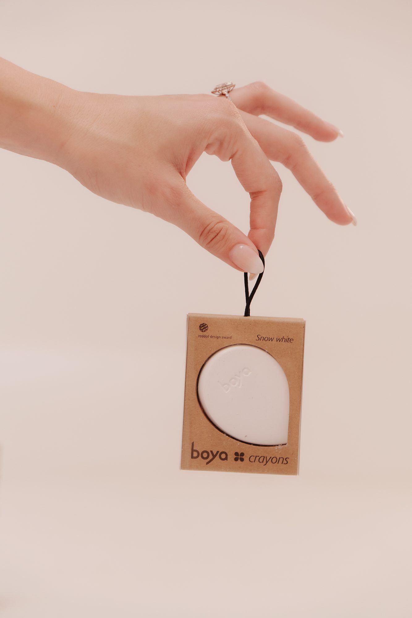 Boya: Hand holding a Boya ornament tag on a white background