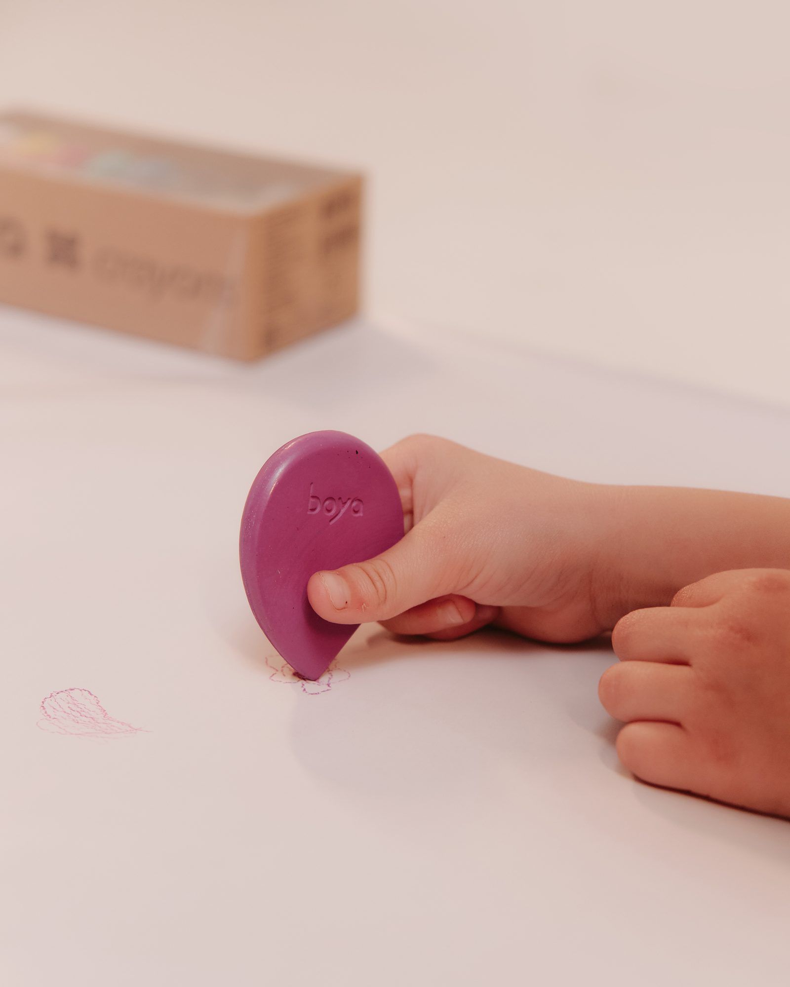 Boya: Child’s hand with a Boya crayon on a white table