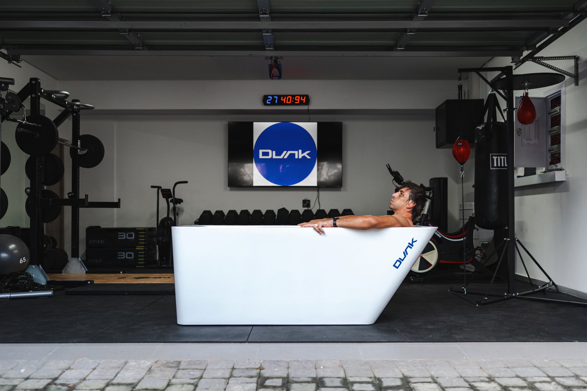 Dunk: Man in a white Dunk ice bath in a home gym, with the Dunk logo on the screen behind