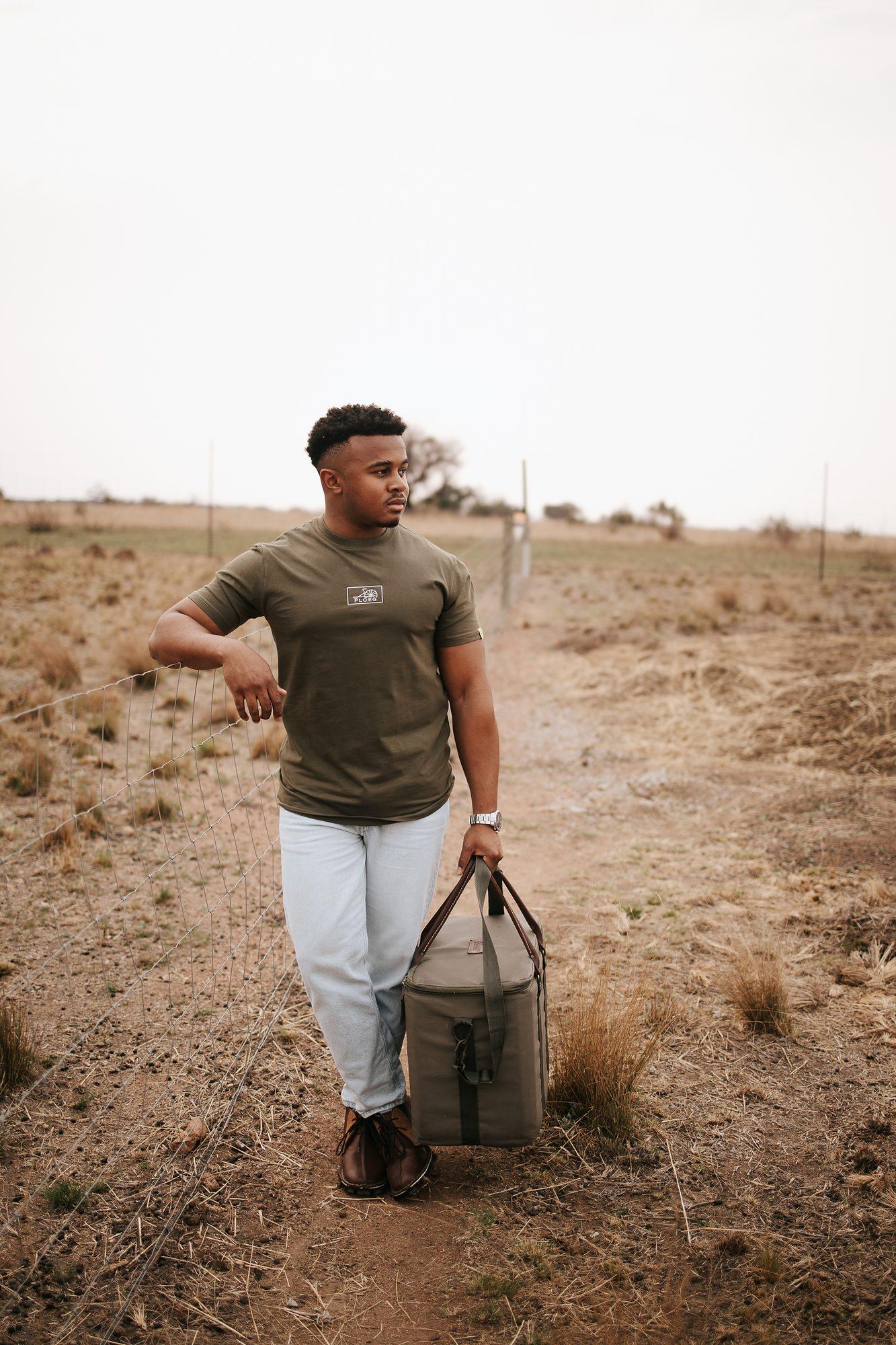 Mieliestronk: Man in an olive tee carrying a bucket across a dry field