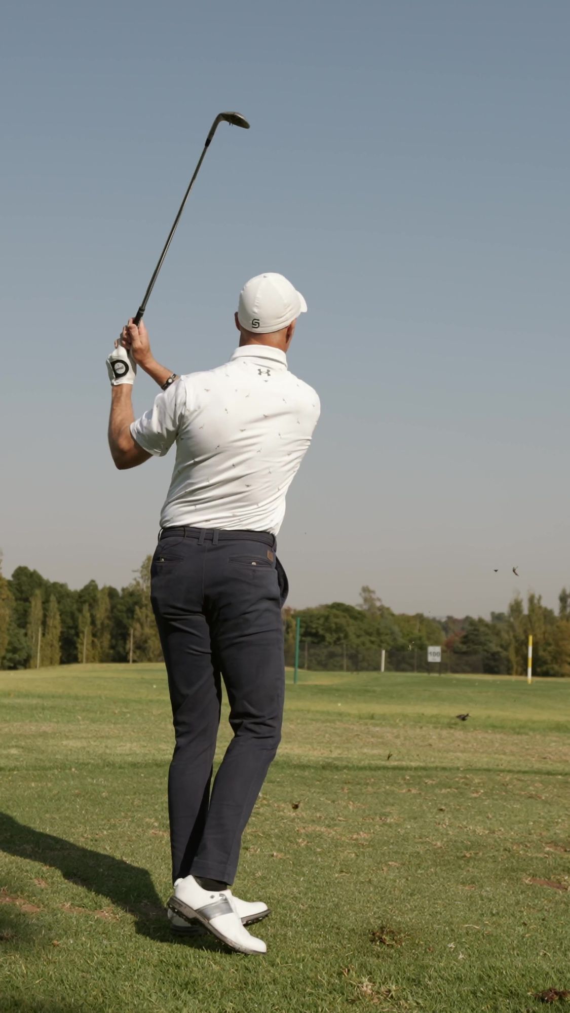 My Golf Pro: Golf pro mid-swing against a clear sky