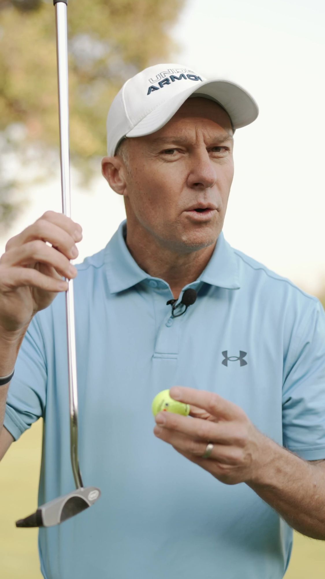 My Golf Pro: Coach in a light-blue polo holding a putter and ball, talking to camera