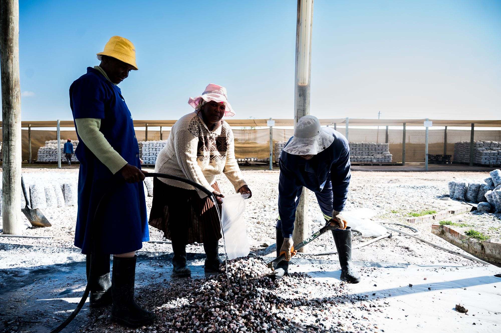 Pebble Africa: Workers in hard hats raking pebbles