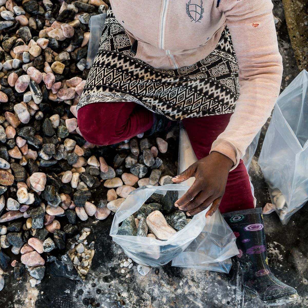 Pebble Africa yard: worker sorting pebbles into a bag by hand