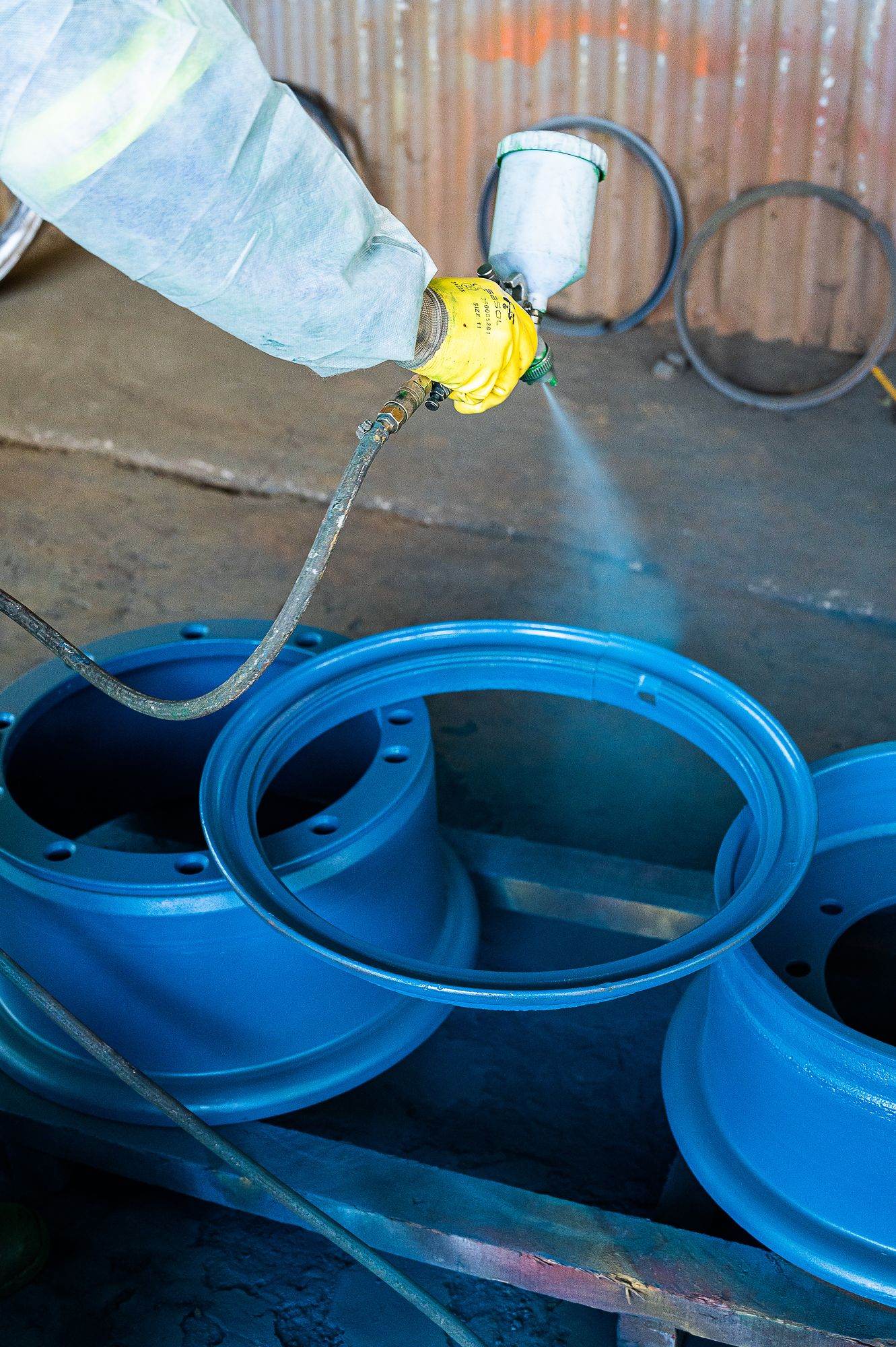 Q Tyres: Hand spray-painting stacked blue wheel rims