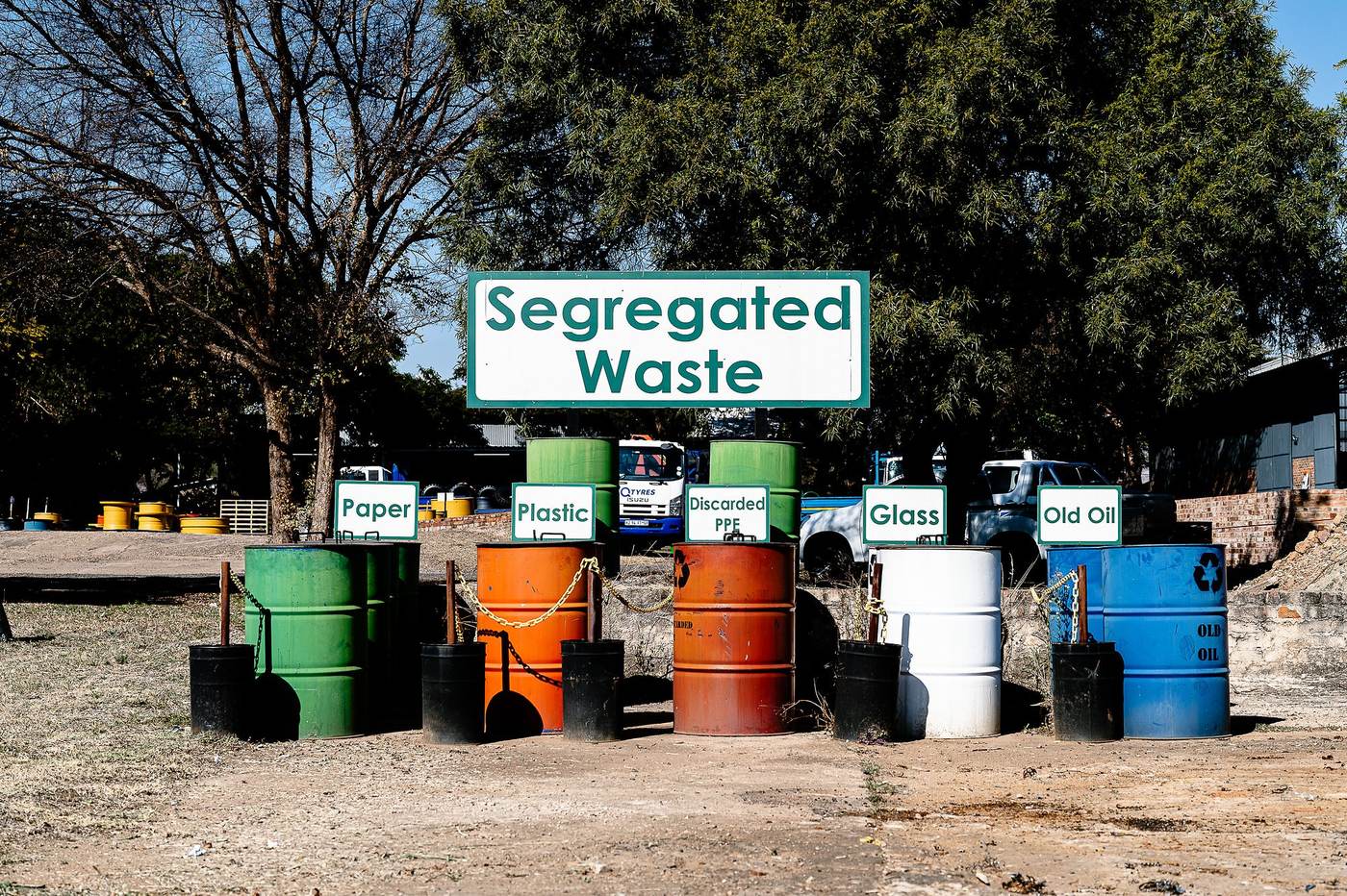 Q Tyres: Colour-coded drums under a “Segregated Waste” sign in the yard