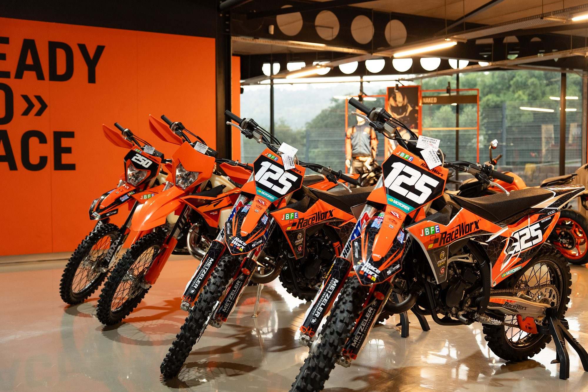 Raceworx: Row of orange KTM motocross bikes in the Raceworx showroom