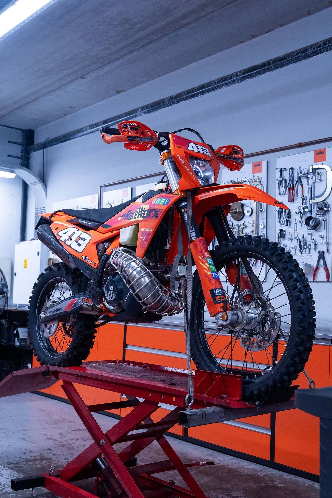 Raceworx: Orange enduro bike on a red lift in the Raceworx workshop