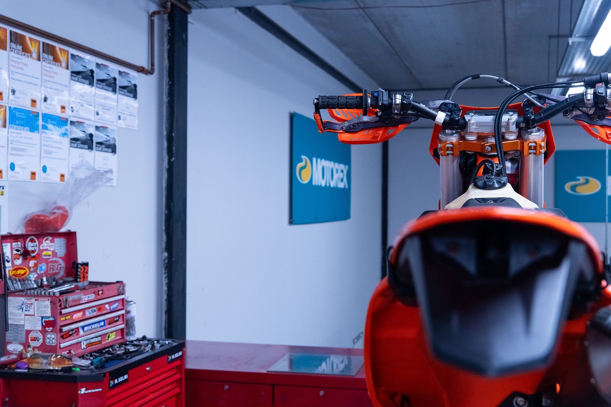 Raceworx: Rear view of an orange dirt bike in the workshop