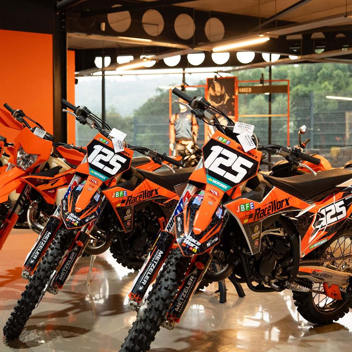 Raceworx dealership shoot: orange KTM dirt bikes lined up in the showroom