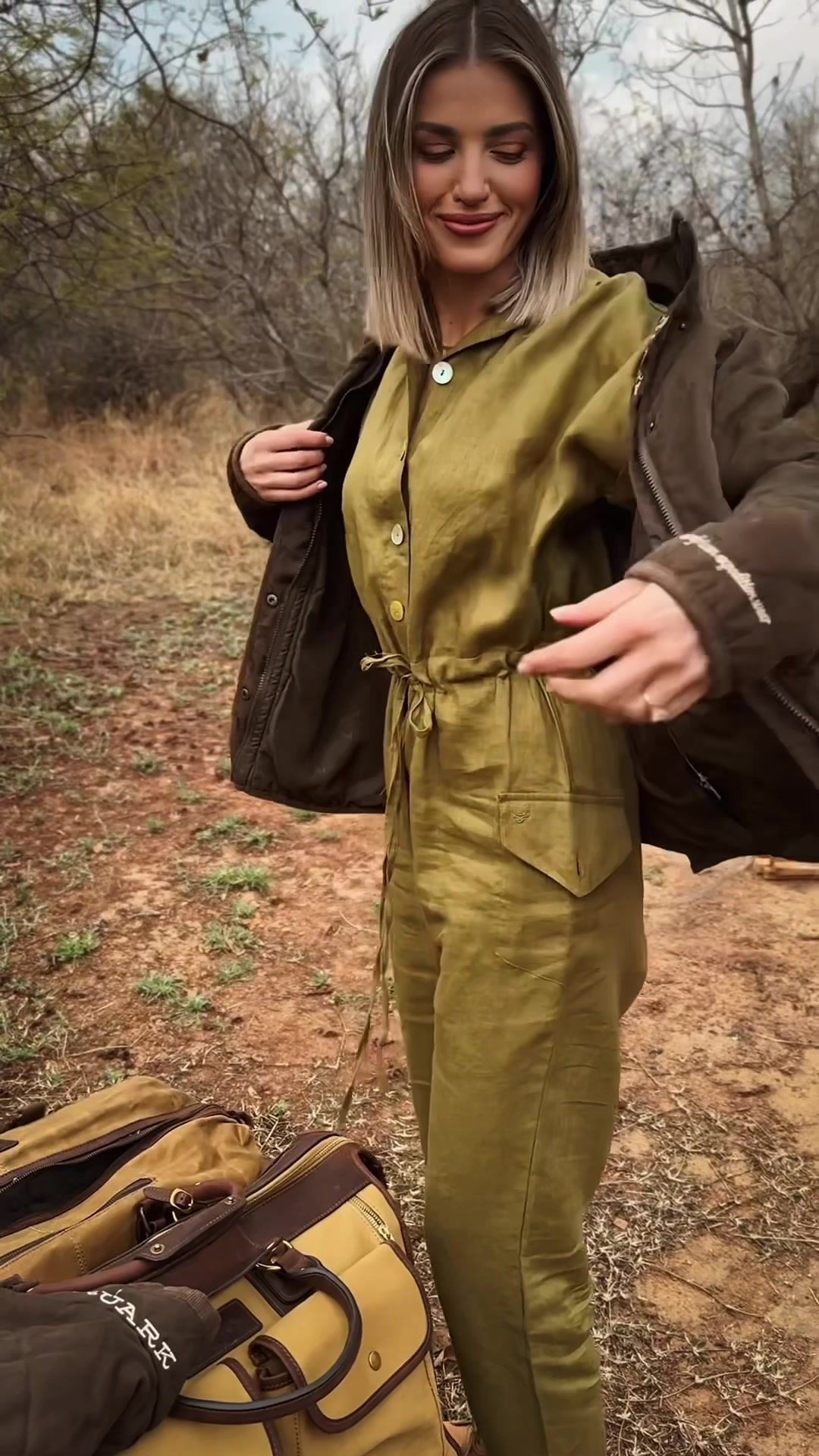 Safari Outdoor: Woman in an olive jumpsuit and waxed jacket in the bushveld