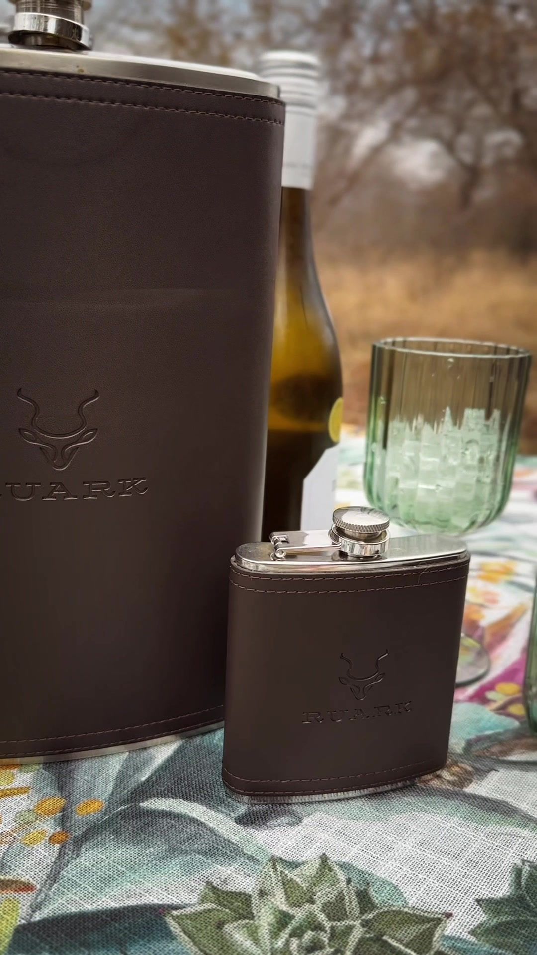 Safari Outdoor: Leather hip flasks and glassware on a picnic blanket